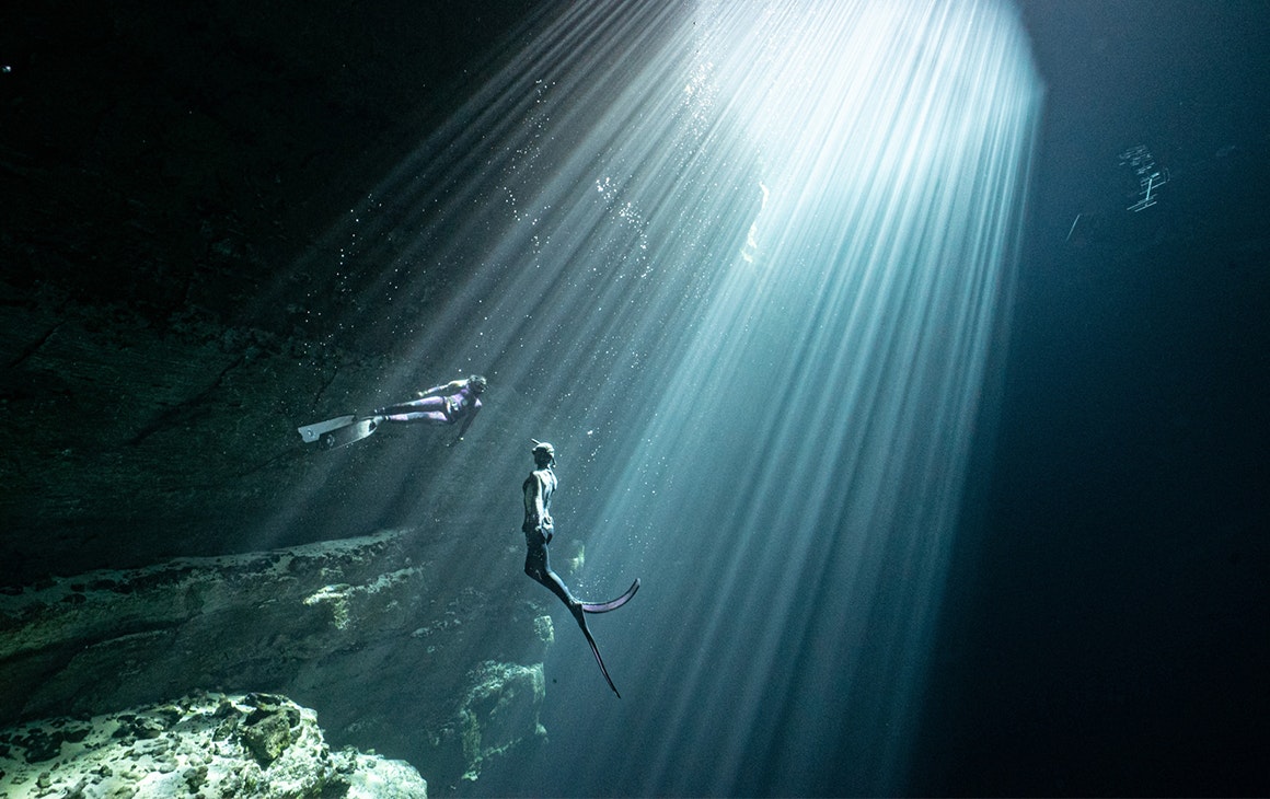two people swim in the deep blue water of the Kilsby Sinkhole